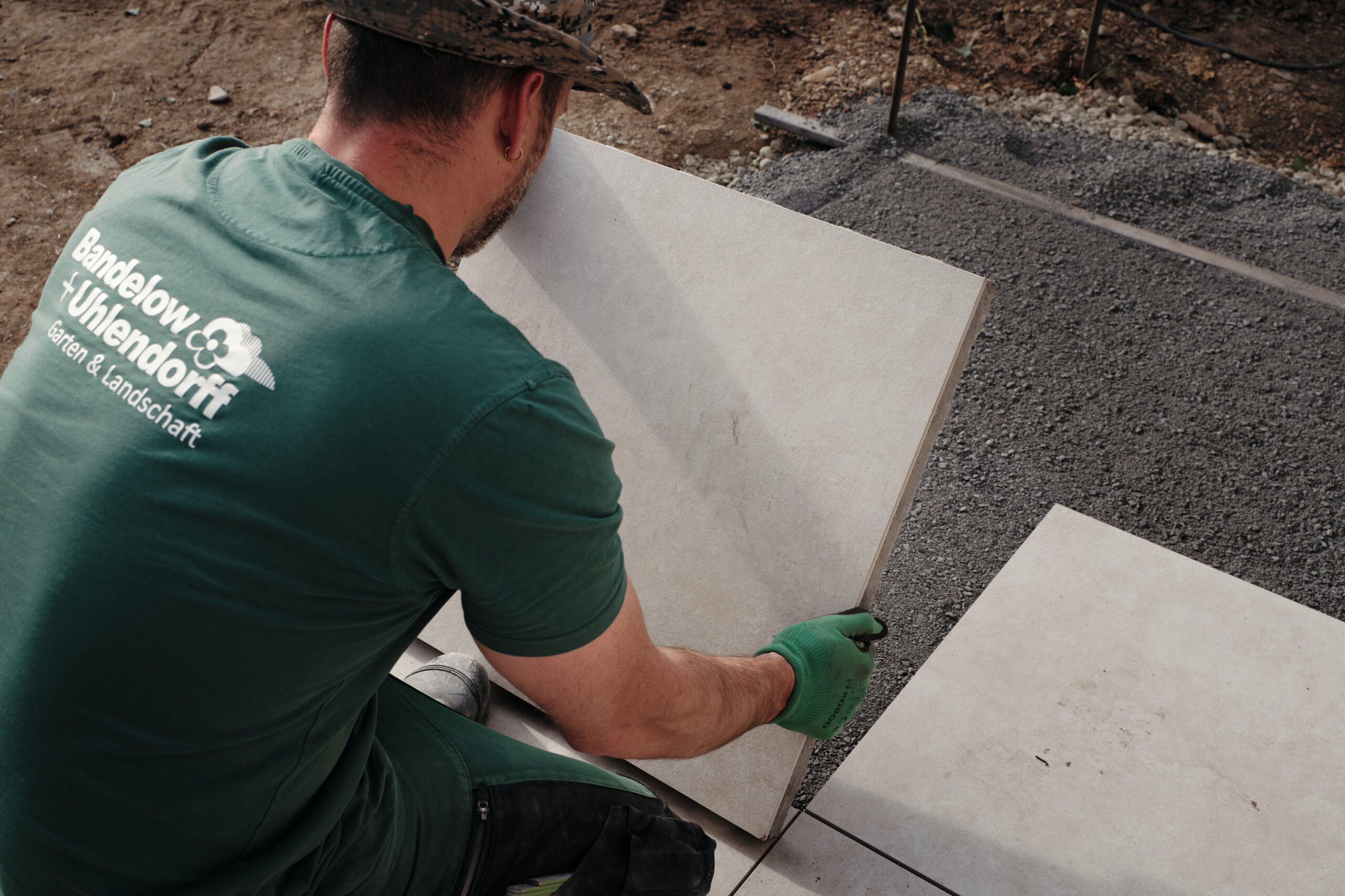 Fachgerechter Terrassenbau in Göttingen: Ein Landschaftsgärtner von Bandelow & Uhlendorff verlegt professionell großformatige Keramikplatten.